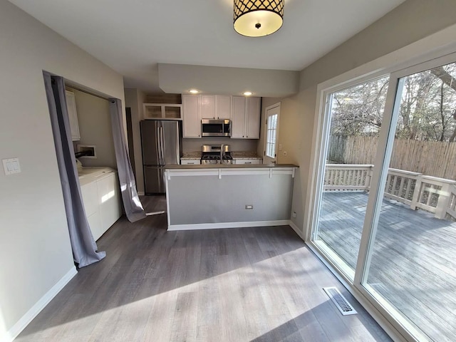 kitchen featuring white cabinetry, sink, dark hardwood / wood-style floors, kitchen peninsula, and appliances with stainless steel finishes