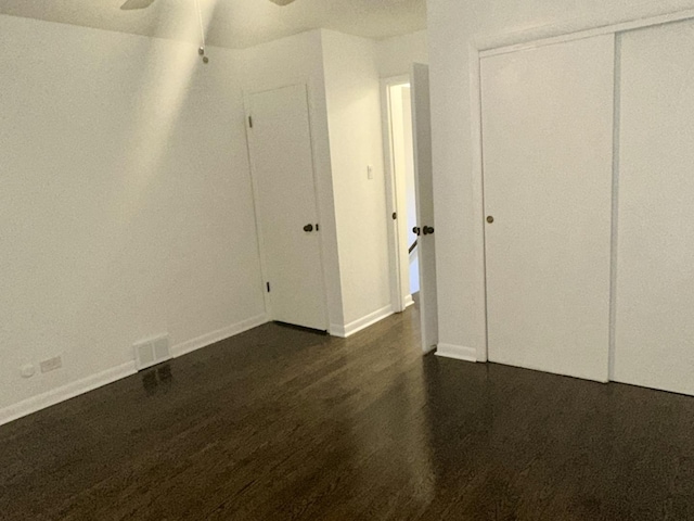 unfurnished bedroom with ceiling fan, a closet, and dark hardwood / wood-style flooring