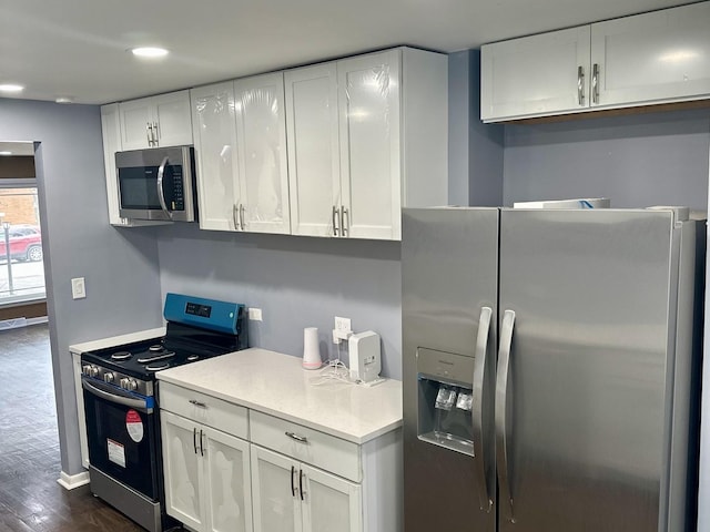 kitchen with white cabinets, appliances with stainless steel finishes, and dark hardwood / wood-style floors