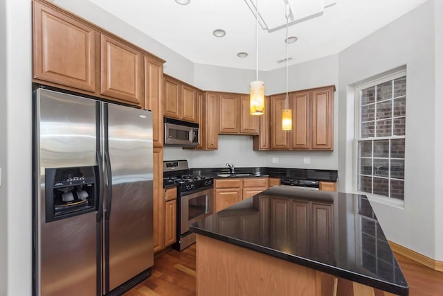 kitchen with sink, hardwood / wood-style flooring, decorative light fixtures, a kitchen island, and stainless steel appliances