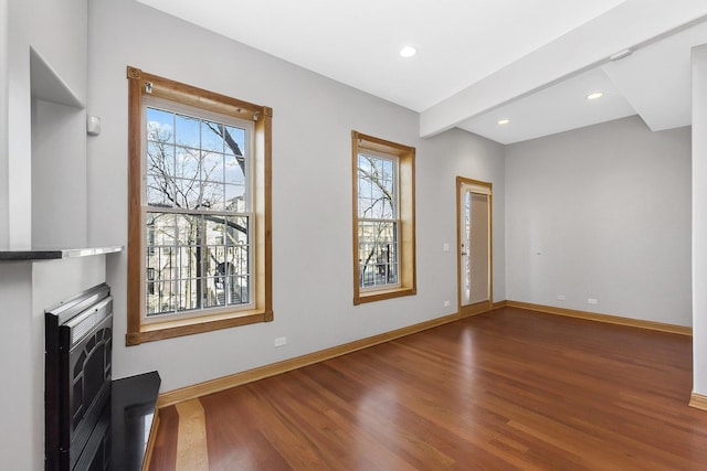 unfurnished living room featuring a healthy amount of sunlight, dark wood-type flooring, and heating unit