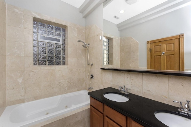 bathroom featuring vanity, backsplash, and tiled shower / bath