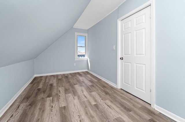 additional living space with hardwood / wood-style floors and vaulted ceiling