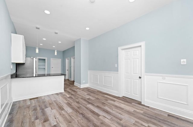 kitchen featuring stainless steel fridge, white cabinetry, pendant lighting, and light hardwood / wood-style floors