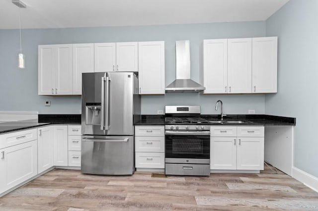 kitchen with wall chimney exhaust hood, stainless steel appliances, pendant lighting, white cabinets, and light wood-type flooring