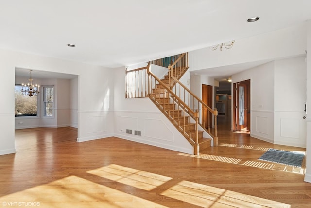 unfurnished living room featuring wood-type flooring and an inviting chandelier