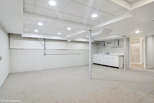 basement with a paneled ceiling, light colored carpet, and sink