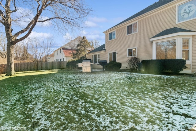 snow covered rear of property featuring a yard