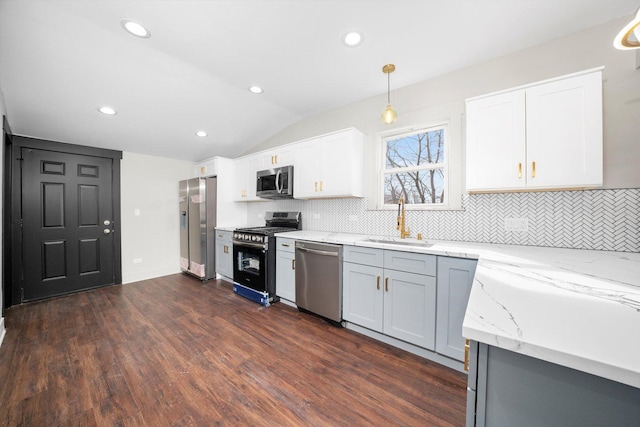 kitchen featuring lofted ceiling, dark wood-style flooring, light stone countertops, stainless steel appliances, and a sink