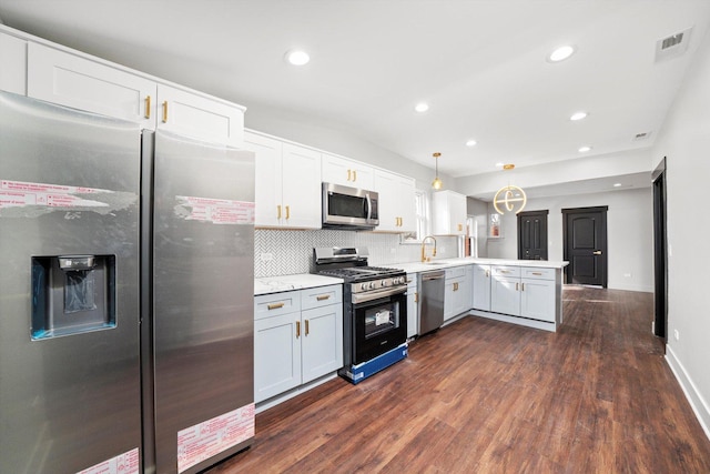 kitchen with a peninsula, dark wood-type flooring, visible vents, appliances with stainless steel finishes, and tasteful backsplash