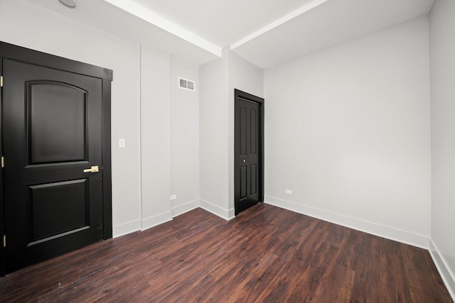 unfurnished bedroom featuring baseboards, visible vents, and dark wood-type flooring