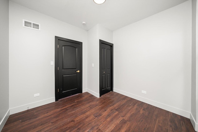 unfurnished bedroom featuring dark wood-style floors, baseboards, and visible vents