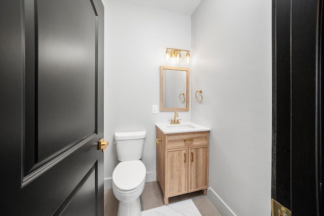 half bathroom with baseboards, vanity, and toilet