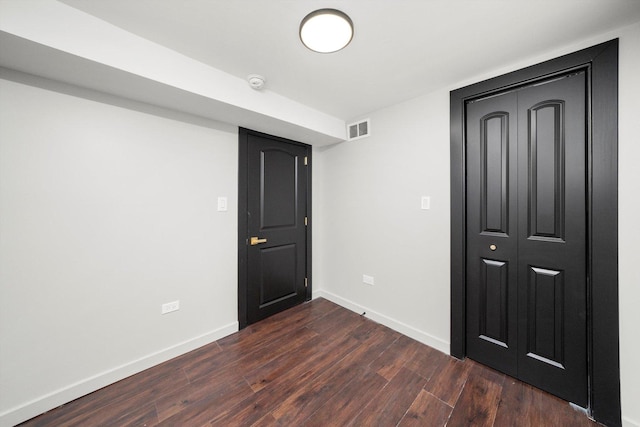 interior space featuring baseboards, visible vents, and dark wood finished floors