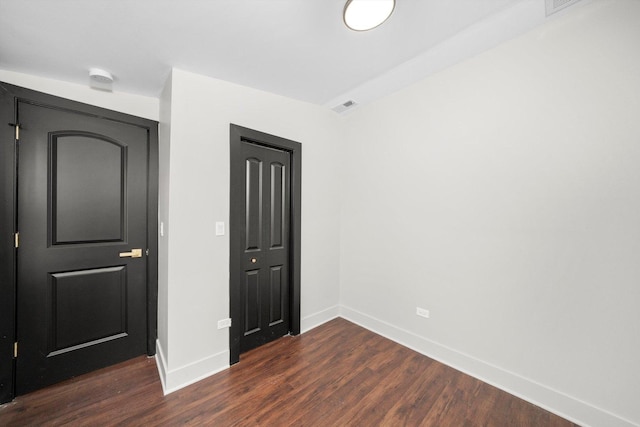 unfurnished bedroom featuring visible vents, dark wood finished floors, and baseboards