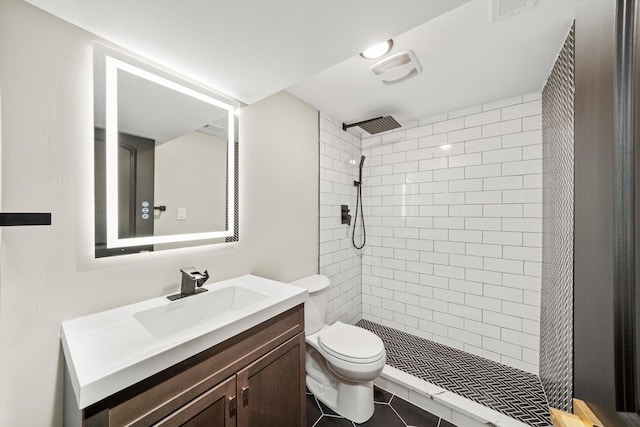 full bathroom with visible vents, toilet, a tile shower, vanity, and tile patterned floors