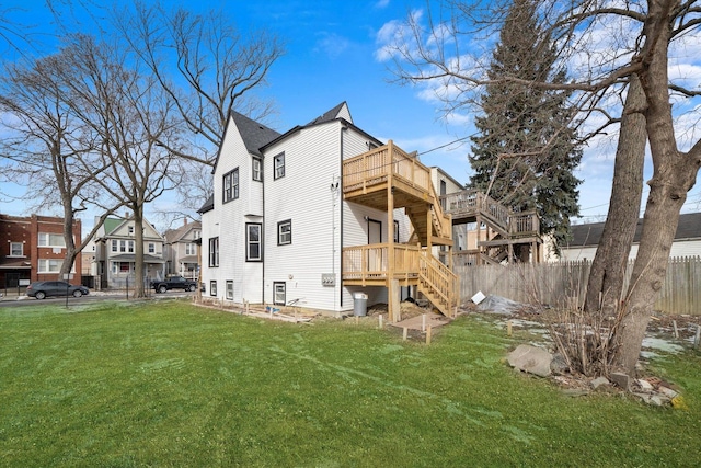 back of house featuring stairs, fence, a deck, and a lawn