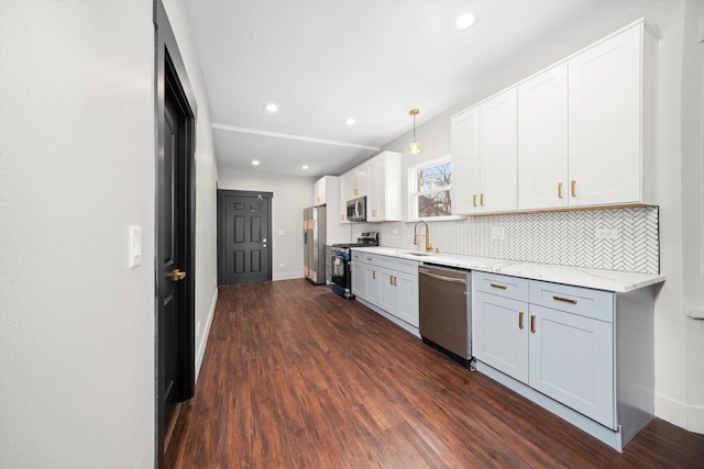 kitchen with white cabinets, appliances with stainless steel finishes, dark wood-type flooring, a sink, and backsplash