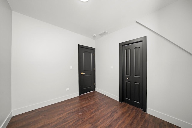 unfurnished room with visible vents, baseboards, and dark wood-style flooring