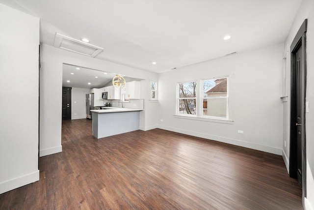 unfurnished living room featuring attic access, baseboards, dark wood finished floors, a sink, and recessed lighting