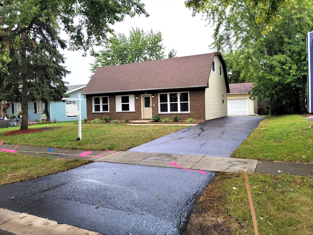 view of front of property featuring a front lawn, an outdoor structure, and a garage