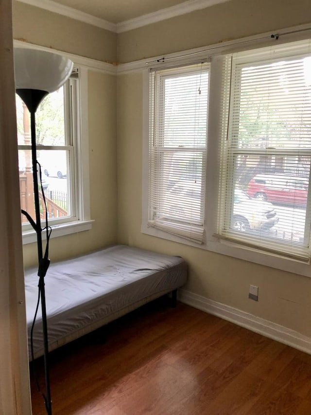 unfurnished bedroom with hardwood / wood-style flooring, multiple windows, and crown molding