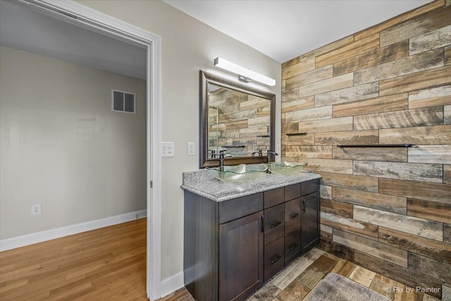 bathroom with vanity, hardwood / wood-style flooring, and wood walls