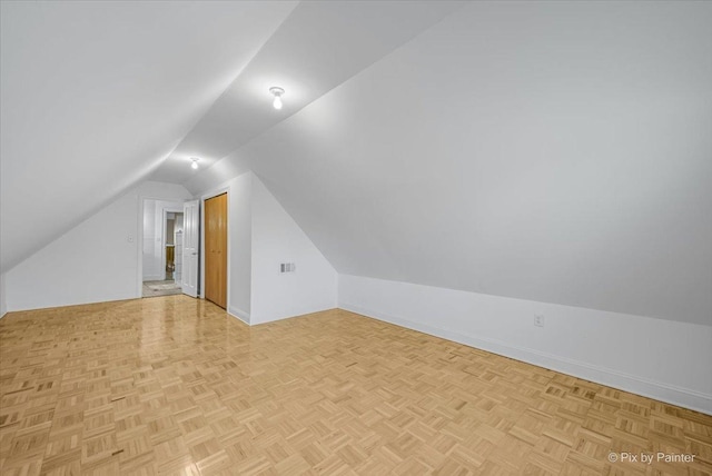 bonus room with light parquet flooring and vaulted ceiling