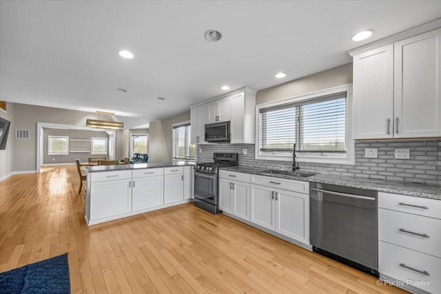 kitchen with kitchen peninsula, sink, white cabinets, and stainless steel appliances