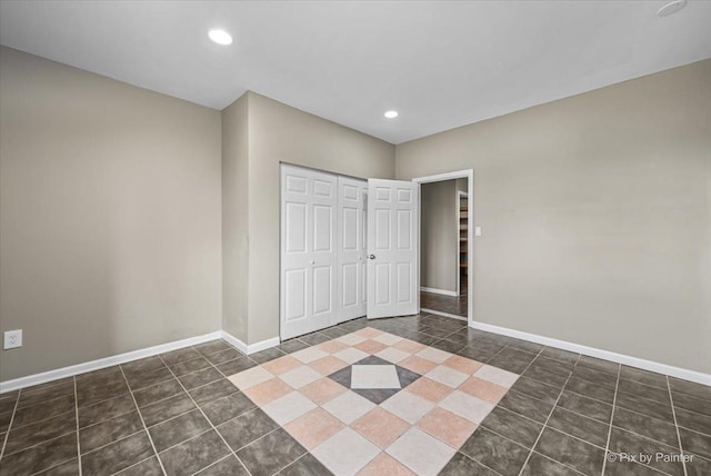 unfurnished bedroom featuring dark tile patterned flooring and a closet