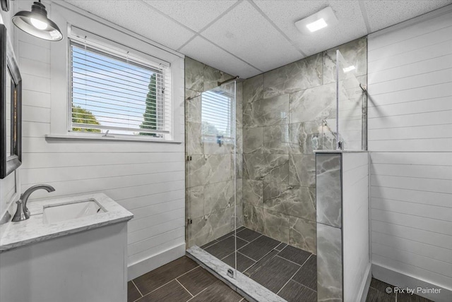 bathroom with vanity, a tile shower, a paneled ceiling, and a wealth of natural light