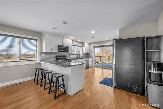 kitchen with sink, kitchen peninsula, a breakfast bar, white cabinets, and appliances with stainless steel finishes