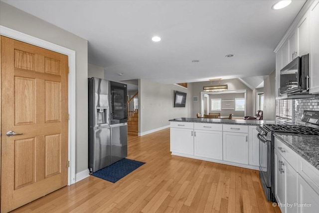 kitchen with backsplash, white cabinets, appliances with stainless steel finishes, light hardwood / wood-style floors, and kitchen peninsula