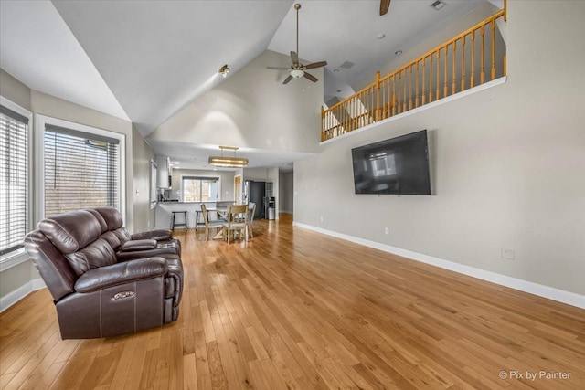 living room with wood-type flooring, high vaulted ceiling, plenty of natural light, and ceiling fan