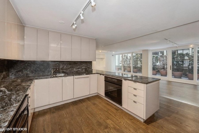 kitchen featuring black appliances, decorative backsplash, dark hardwood / wood-style floors, and white cabinetry