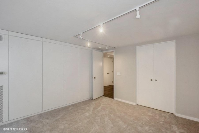 interior space featuring light colored carpet and track lighting