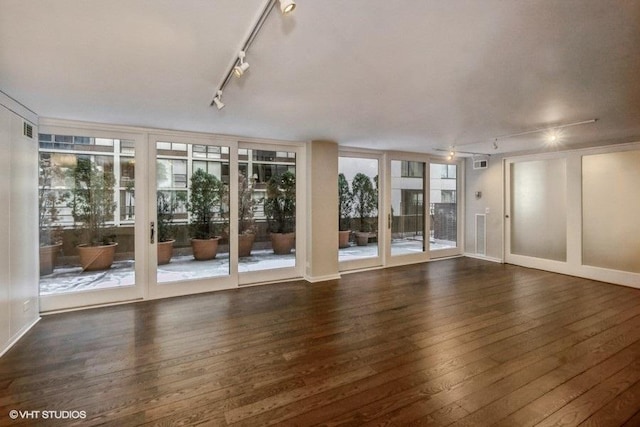 unfurnished living room with dark hardwood / wood-style flooring and rail lighting