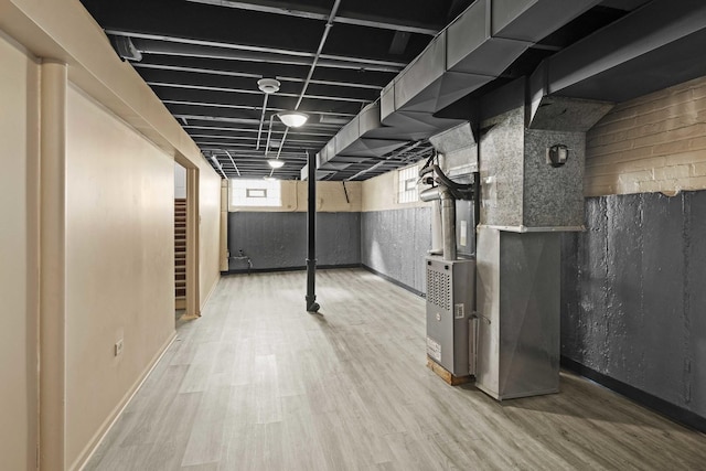 basement featuring hardwood / wood-style flooring and heating unit