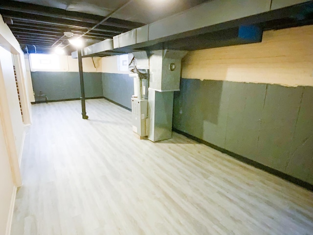 basement with heating unit and light hardwood / wood-style flooring