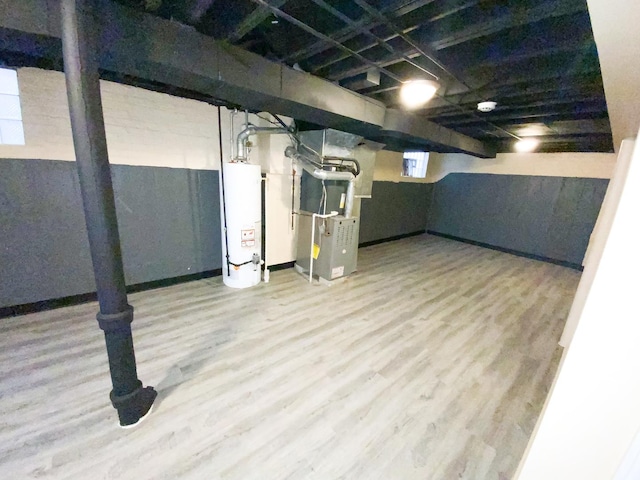 basement with light hardwood / wood-style floors, gas water heater, and heating unit