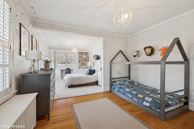 bedroom featuring wood finished floors, baseboards, ornamental molding, radiator, and an inviting chandelier