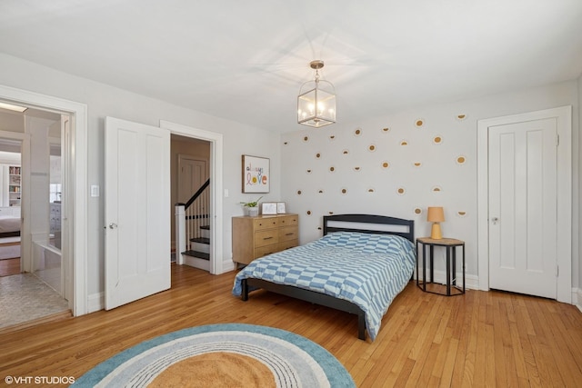 bedroom featuring a notable chandelier, light wood-style flooring, and baseboards