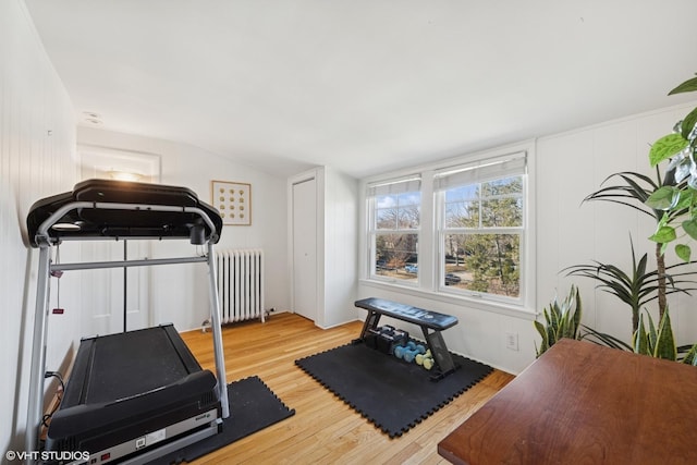 workout room featuring vaulted ceiling, light wood finished floors, and radiator heating unit