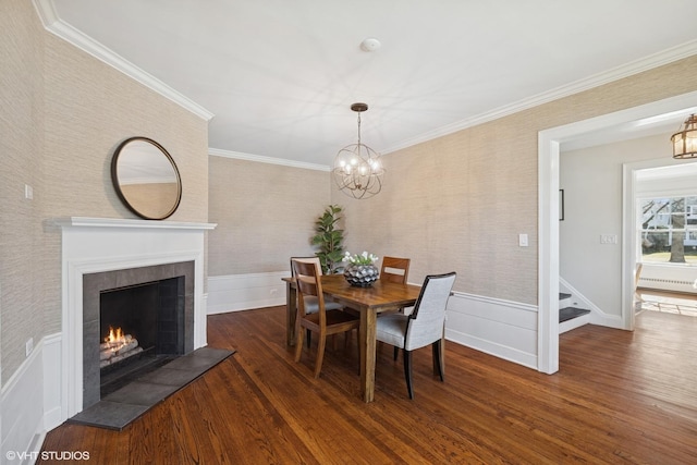 dining space with crown molding, wainscoting, wood finished floors, a tile fireplace, and wallpapered walls