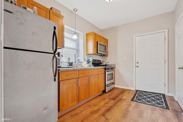 kitchen featuring pendant lighting, light wood-type flooring, and stainless steel appliances