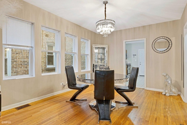 dining area featuring light wood-type flooring and a notable chandelier