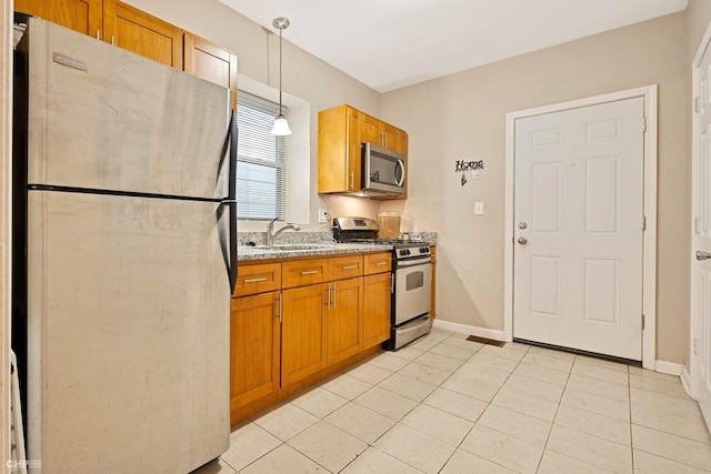 kitchen featuring pendant lighting, sink, light tile patterned floors, appliances with stainless steel finishes, and light stone counters