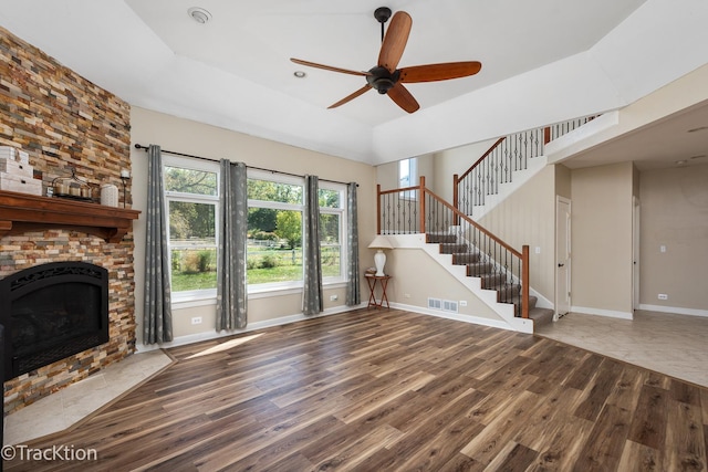 unfurnished living room featuring hardwood / wood-style flooring, ceiling fan, a raised ceiling, and a fireplace