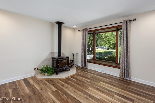 unfurnished living room with hardwood / wood-style floors and a wood stove