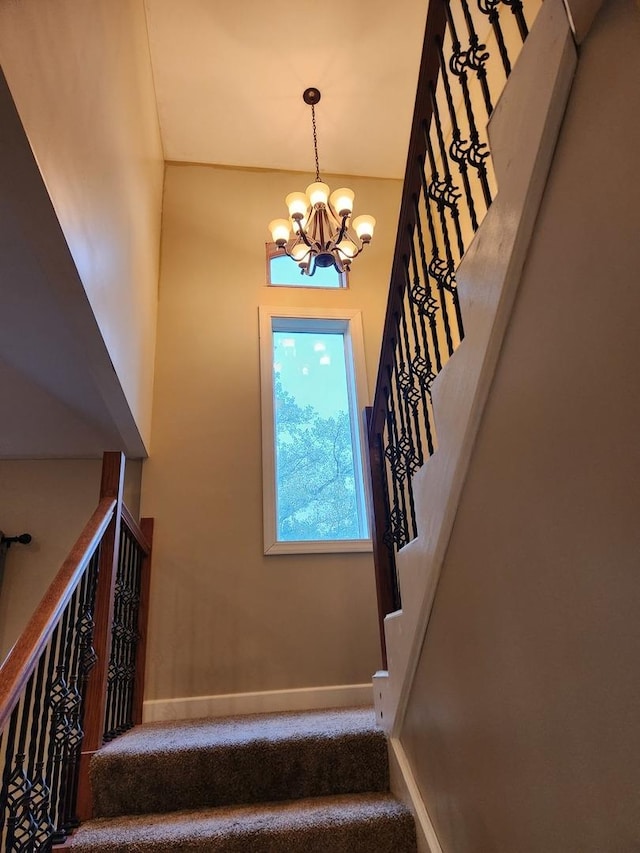 stairway featuring carpet floors and a chandelier